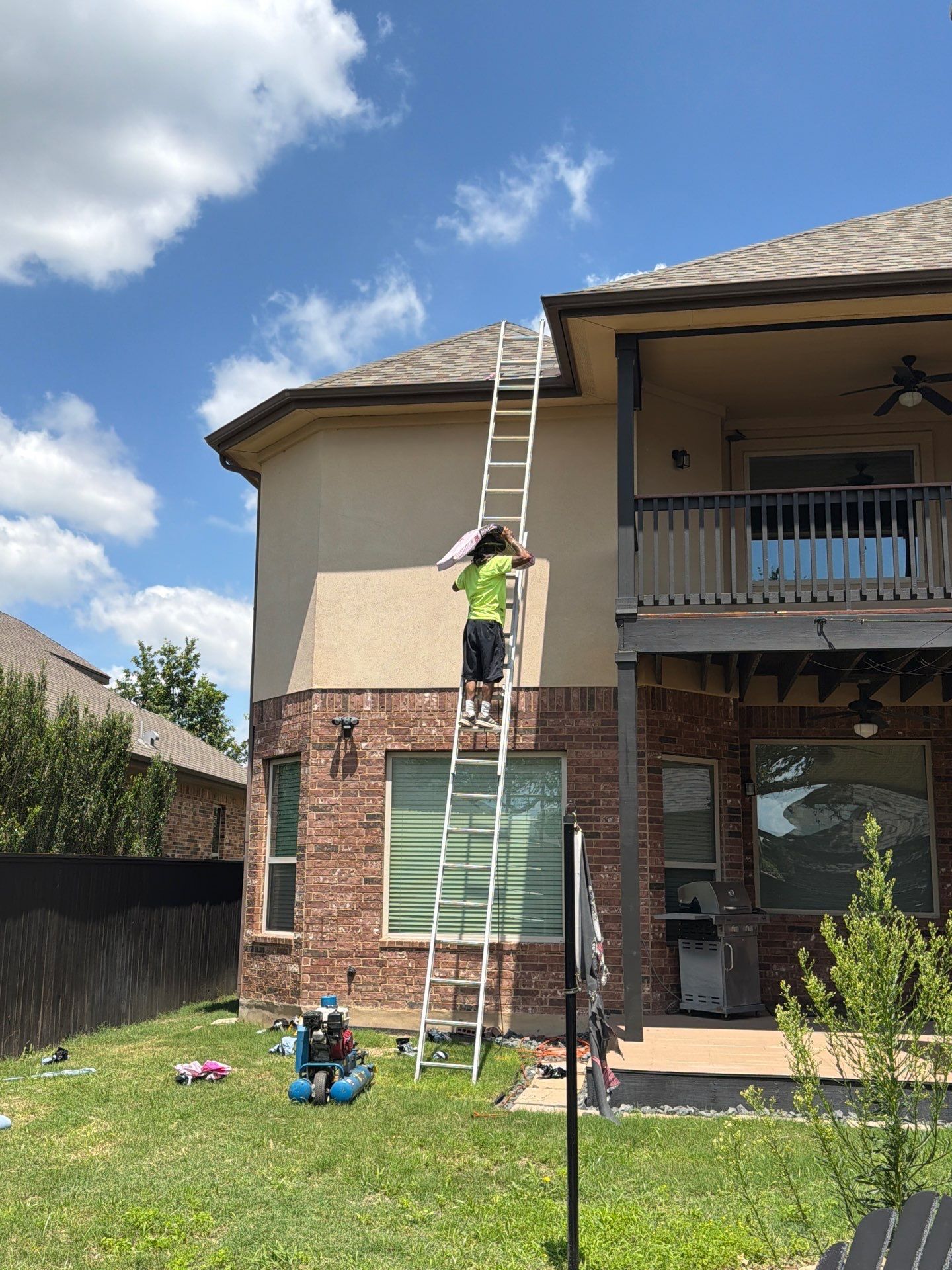 Divided Sky crew member carrying a single bundle of shingles up a ladder for a roof repair