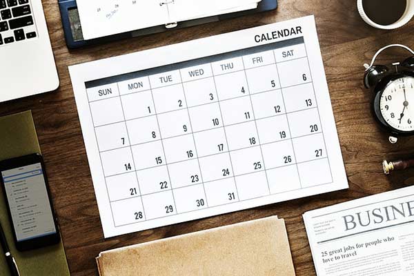 A calendar sits on a desk with other productivity tools.