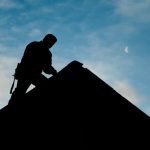 A roofer conducts a roof inspection silhouetted against an evening sky. roofing san marcos