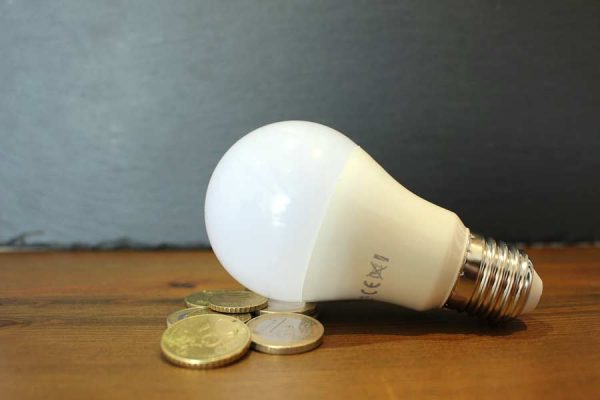 A lightbulb on a desk with some coins that you can use on roofing in New Braunfels TX