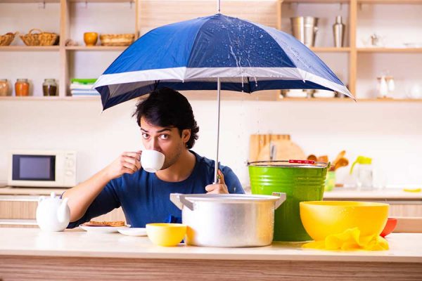 Man holding an umbrella to shield against a roof leak