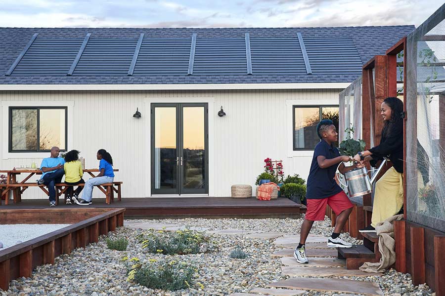 Family working in a garden outside a home with solar shingles