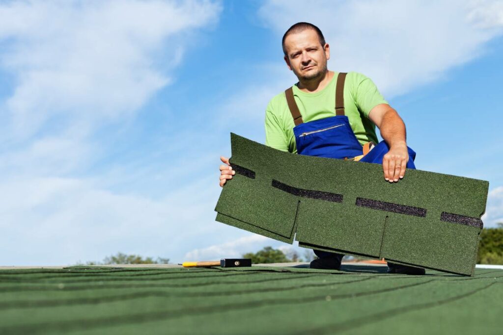 Professional roofer holding a brand new asphalt shingle to be installed on a roof