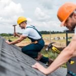 two roofing professionals working on a roof