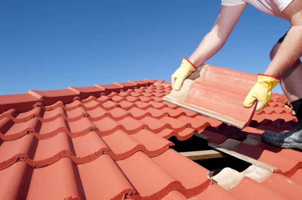 A worker replacing tiles after finding damage during a free roof inspection in San Marcos.
