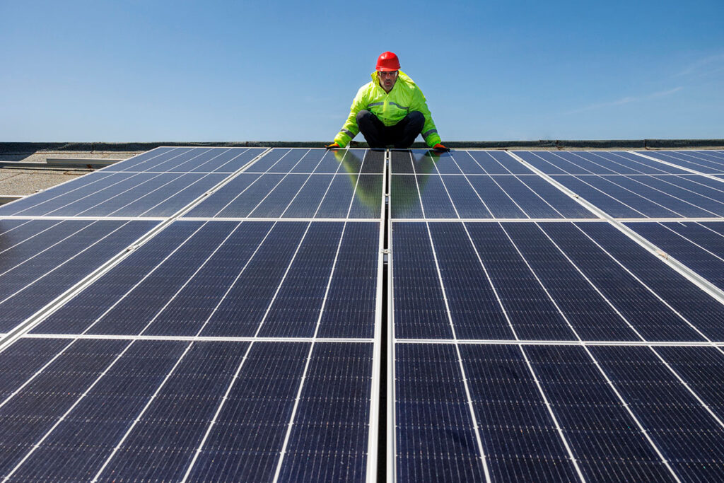 A roofer inspects Austin commercial solar panels on a sunny day.