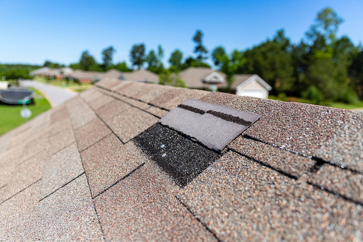 A roof is missing shingles due to storm damage.